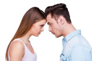 Relationships without any compromise.  Side view of young couple standing face to face and looking at each other while standing against white background photo