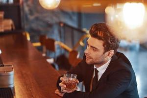 vista superior de un joven apuesto con traje completo bebiendo alcohol foto