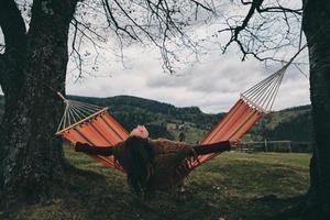 Best place to rest.  Beautiful young woman lying in hammock while relaxing on the valley under the tree photo