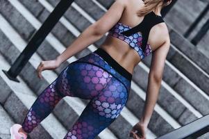 Ready to overcome any obstacle. Close up rear view of young woman in sport clothing moving up the stairs while exercising outdoors photo