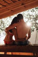 Just relaxing.  Rear view of young couple embracing while resting in the beach hut together photo