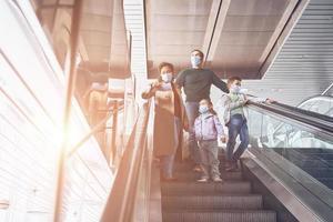 Family with two little kids moving by escalator in airport terminal photo