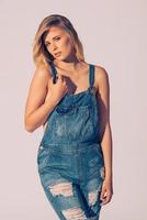 Denim style. Studio shot of beautiful young woman in jeans overall looking at camera photo
