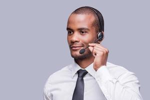 Providing best support. Confident young African man adjusting his headset and looking away while standing against grey background photo