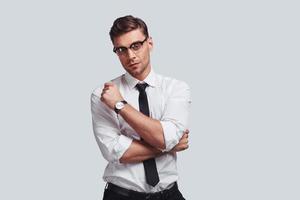 Thoughtful man. Good looking young man looking at camera while standing against grey background photo