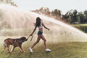 toda la longitud de una hermosa joven jugando con su perro mientras corre al aire libre foto