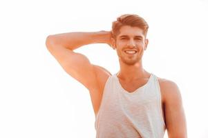 Fit and confident. Low angle view of young muscular man posing and looking at camera while standing against sky photo