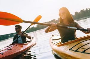 Enjoying nice day on river. Beautiful young couple kayaking on lake together and smiling photo