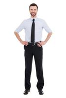 Confident businessman. Full length of confident young businessman in shirt and tie looking at camera and smiling while standing against white background photo