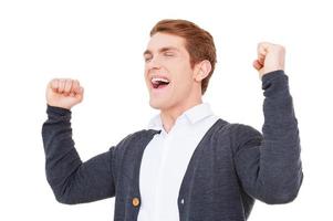 Everyday winner. Cheerful young man keeping arms raised and expressing positivity while standing isolated on white photo