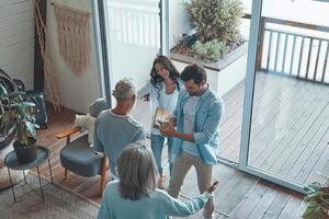 Top view of happy senior parents meeting young couple inside the house photo