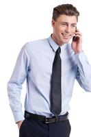 Great news Handsome young man in formalwear talking on the mobile phone and smiling while standing isolated on white photo