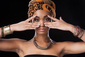 Queen of Africa. Beautiful African woman wearing a headscarf and looking at camera while standing against black background photo