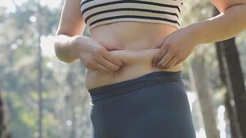 belle grosse femme avec ruban à mesurer, elle utilise sa main pour presser l'excès de graisse isolé sur fond blanc. elle veut perdre du poids, le concept de chirurgie et décomposer les graisses sous le video