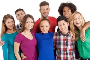 We are team Group of cheerful young multi-ethnic people standing close to each other and smiling at camera while standing isolated on white photo