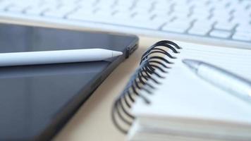 Notebook with pen and tablet next to it video