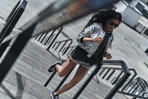 On the move. Beautiful young woman in casual wear running up the stairs outdoors photo