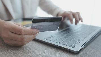 manos de mujer sosteniendo y usando tarjeta de crédito para comprar en línea.
