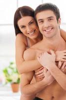 Spending morning time together. Cheerful young loving couple sitting together in bed and holding photo