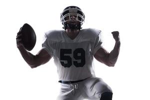 Shout of joy.  American football player screaming and standing on knee against white background photo