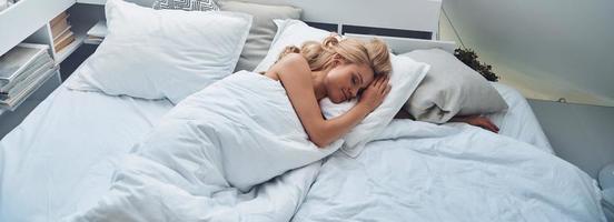 Top view of beautiful young blond hair woman sleeping in bed and covered with blanket photo