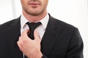 buen negocio. imagen recortada de un joven con ropa formal ajustándose la corbata foto