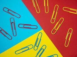 Colored paper clips on paper. Office supplies.  Colorful office supplies. photo