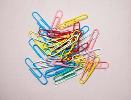 Colored paper clips on paper. Office supplies. Business goods. photo
