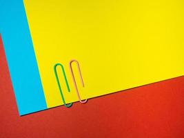 Colored paper clips on paper. Office supplies.   Colorful office supplies. photo