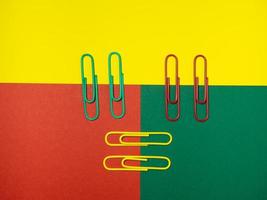 Colored paper clips on paper. Office supplies.   Colorful office supplies. photo