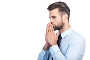 pensando en el futuro. vista lateral de un joven apuesto y pensativo con camisa y corbata sosteniendo la mano en la barbilla y mirando hacia otro lado mientras se enfrenta a fondo blanco foto