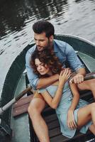 She is the center of his universe. Top view of beautiful young couple embracing and looking away while enjoying romantic date on the lake photo