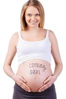próximamente, en breve, pronto. imagen recortada de una mujer embarazada con un cartel de "próximamente" en su vientre aislado en blanco foto
