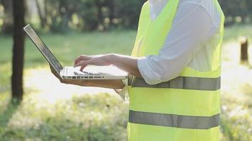 smart asiatisk arbetstagare man eller manlig civil ingenjör med skyddande säkerhet hjälm och reflekterande väst använder sig av digital läsplatta för projekt planera och kontroll arkitektonisk teckning på konstruktion webbplats. video