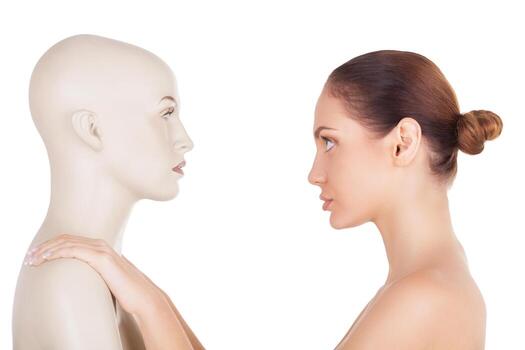Real or artificial Side view of beautiful young shirtless woman standing in front of the mannequin and looking at it while standing isolated on white background photo