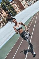 Pushing hard to win. Full length top view of young woman in sports clothing jogging while exercising outdoors photo