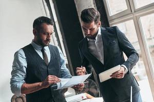 Developing new project. Two young modern men in formalwear working together while standing indoors photo