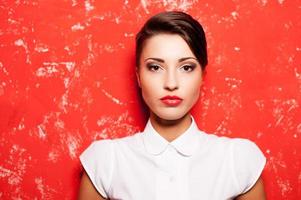 belleza en rojo. hermosa joven mujer de pelo corto con camisa blanca posando sobre fondo rojo foto