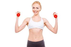 Strong and healthy. Beautiful mature women holding dumbbells and smiling while standing against white background photo
