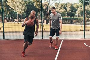 New champion. Two young men in sports clothing playing basketball while spending time outdoors photo