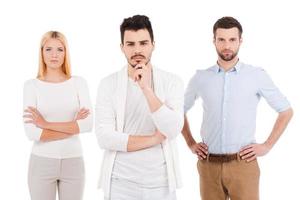 Confident young professionals. Three confident young people in smart casual wear looking at camera while standing against white background photo