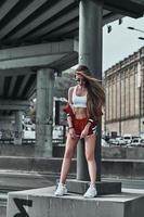 Beautiful and sporty. Full length of attractive young woman in sport clothing posing while standing outdoors photo