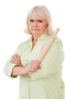 Where have you been Angry senior woman holding rolling pin and looking at camera while standing isolated on white background photo