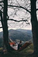 Free your mind. Handsome young man lying in hammock while camping with his girlfriend photo