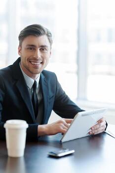 Checking through his inbox. A handsome businessman using his tablet while sitting and having a break photo