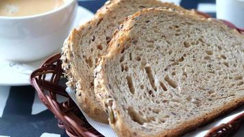 Slices of artisan seeded bread in a basket next to a cup of coffee or tea video