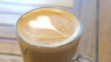 vicino su di cuore latte macchiato arte schiuma nel un' chiaro bicchiere boccale video