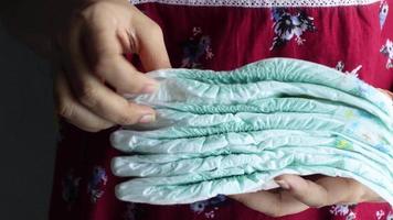Holding a pile of new disposable diapers video
