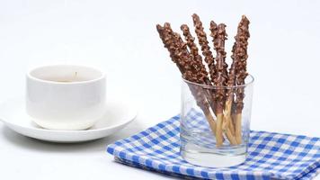 Chocolate covered breadsticks in a glass cup next to ceramic mug video