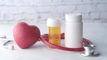 A stethoscope and pill containers on a white table